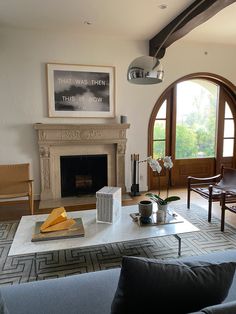 a living room filled with furniture and a fire place in front of a large window