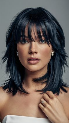 A medium-length cut with blunt bangs and layers creates a chic, structured look that stands out. The contrast between the blunt bangs and soft layers gives this style a contemporary feel, perfect for long straight or long wavy textures. It works well for oval and long face shapes, as the bangs help balance the length of the face while the layers add movement to the hair. Rachel Haircut With Bangs, Layered Bangs Medium Hair, Long Inverted Bob With Bangs, Mid Length Bob With Layers, Goth Haircut Medium, Medium Length Haircuts With Layers, Trendy Medium Length Haircuts, Long Wavy Layers, Hair And Skin Vitamins