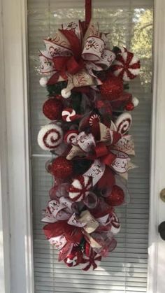 a christmas wreath hanging from the front door with candy canes and bows on it