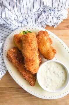 two fried food items on a plate with dipping sauce