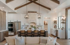 a living room filled with furniture next to a kitchen and dining room table covered in white pillows