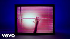 a person's hand reaching out through the blinds in front of a blue background