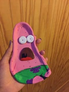 a hand holding a pink spongebob shaped phone case with googly eyes on it