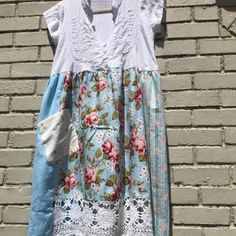 a dress hanging on a brick wall next to a white and blue shirt with flowers