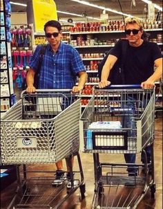 two men pushing shopping carts in a grocery store