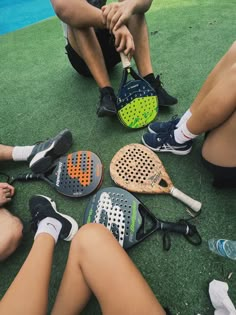 four people sitting on the ground with tennis rackets