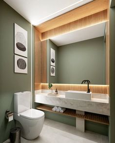 a modern bathroom with green walls and white counter tops, along with an open toilet