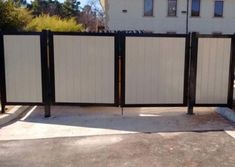 an open gate in front of a white building with black metal bars on the sides