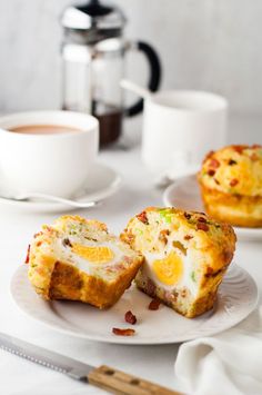 two muffins are sitting on a plate next to some cups and saucers