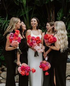 a group of women standing next to each other holding bouquets in their hands and laughing