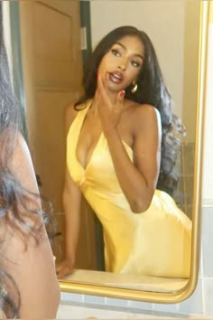 a woman in a yellow dress looking at herself in the mirror and brushing her teeth