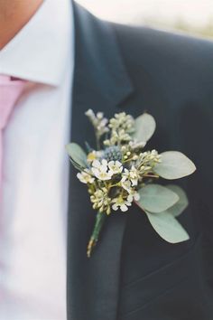 a man wearing a suit and pink tie holding a boutonniere with flowers on it