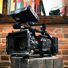 a video camera sitting on top of a wooden box in front of a brick wall