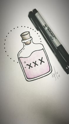 a bottle with crosses drawn on it sitting next to a marker and some ink pens