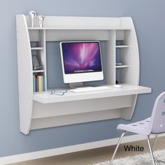 a desk with a computer on it and a chair next to it in front of a blue wall