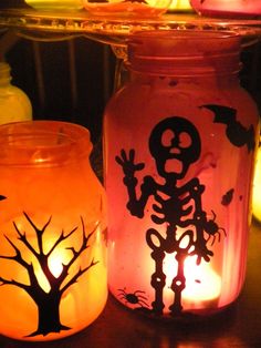 two jars with halloween decorations and candles in them