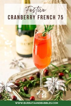 a glass of cranberry french 75 next to a bottle of wine on a tray