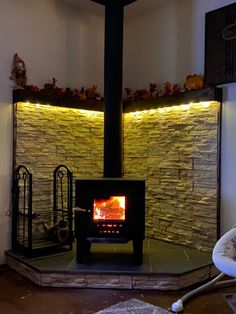 a fire place in the middle of a room with a stone wall behind it and lights on