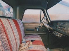 the interior of an old pickup truck with red and white striped seat covers on it