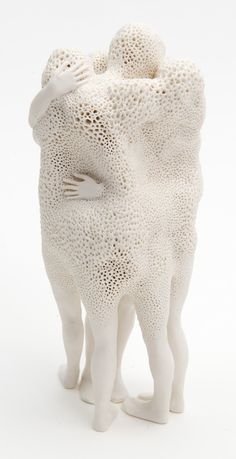 a sculpture of two people hugging each other with their arms around one another, on a white background