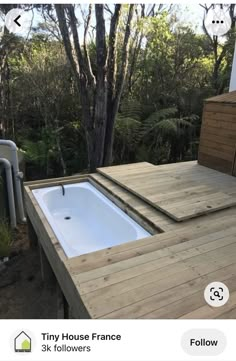 a hot tub sitting on top of a wooden deck next to a tree filled forest