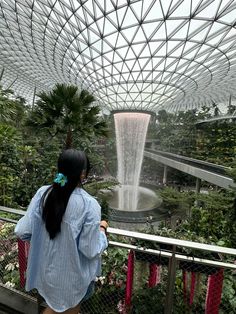 a woman standing in front of a waterfall at the gardens by the bay, singapore