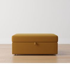 an orange ottoman sitting on top of a hard wood floor next to a white wall