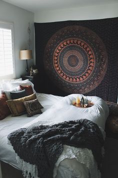 a bedroom with a large tapestry hanging over the headboard and pillows on the bed