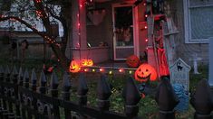 a house decorated for halloween with pumpkins and lights