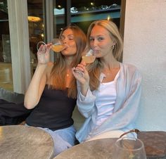 two women sitting at a table drinking wine