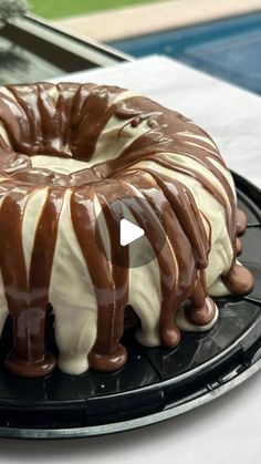 a chocolate bundt cake with white frosting on a black plate