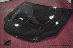 the hood of a black sports car on a wooden floor