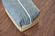 a gray and yellow bag sitting on top of a wooden floor