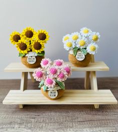 three small baskets with flowers are sitting on a shelf