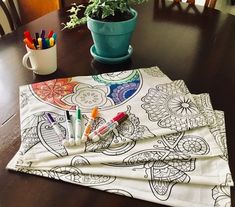 two napkins with markers on them sitting on a table next to a potted plant