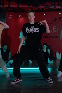 the young man is practicing his moves on the dance floor with other people in the background