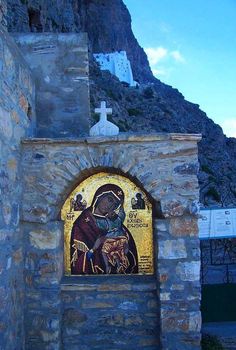 a stone wall with a painting on it and a cross at the top of it