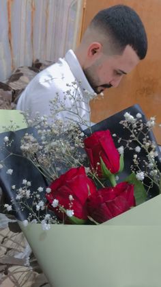 a man in white shirt and tie holding red roses