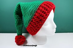 a green and red knitted hat sitting on top of a white mannequin head