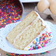 a slice of cake on a plate with sprinkles and eggs in the background