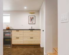 an empty kitchen with wooden cabinets and black counter tops, along with stairs leading up to the second floor