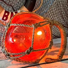 a red light sitting on top of a wooden table next to a netted bag