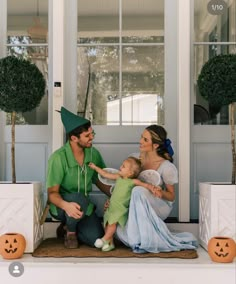 a man, woman and child are sitting on the front porch with halloween decorations around them