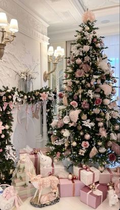 a decorated christmas tree with pink and white presents in front of it on a table