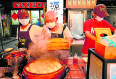 three men wearing masks cooking food on an outdoor grill