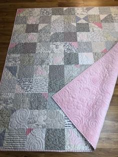 a pink and grey quilt on the floor