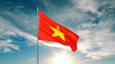 the vietnamese flag is flying high in the blue sky with sun shining behind it and some clouds