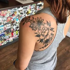 a woman with a flower tattoo on her back shoulder and arm is looking at the camera