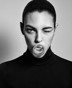 a black and white photo of a woman with an object in her mouth