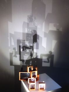 shadows cast on the wall and table in front of it, with small wooden frames arranged around them